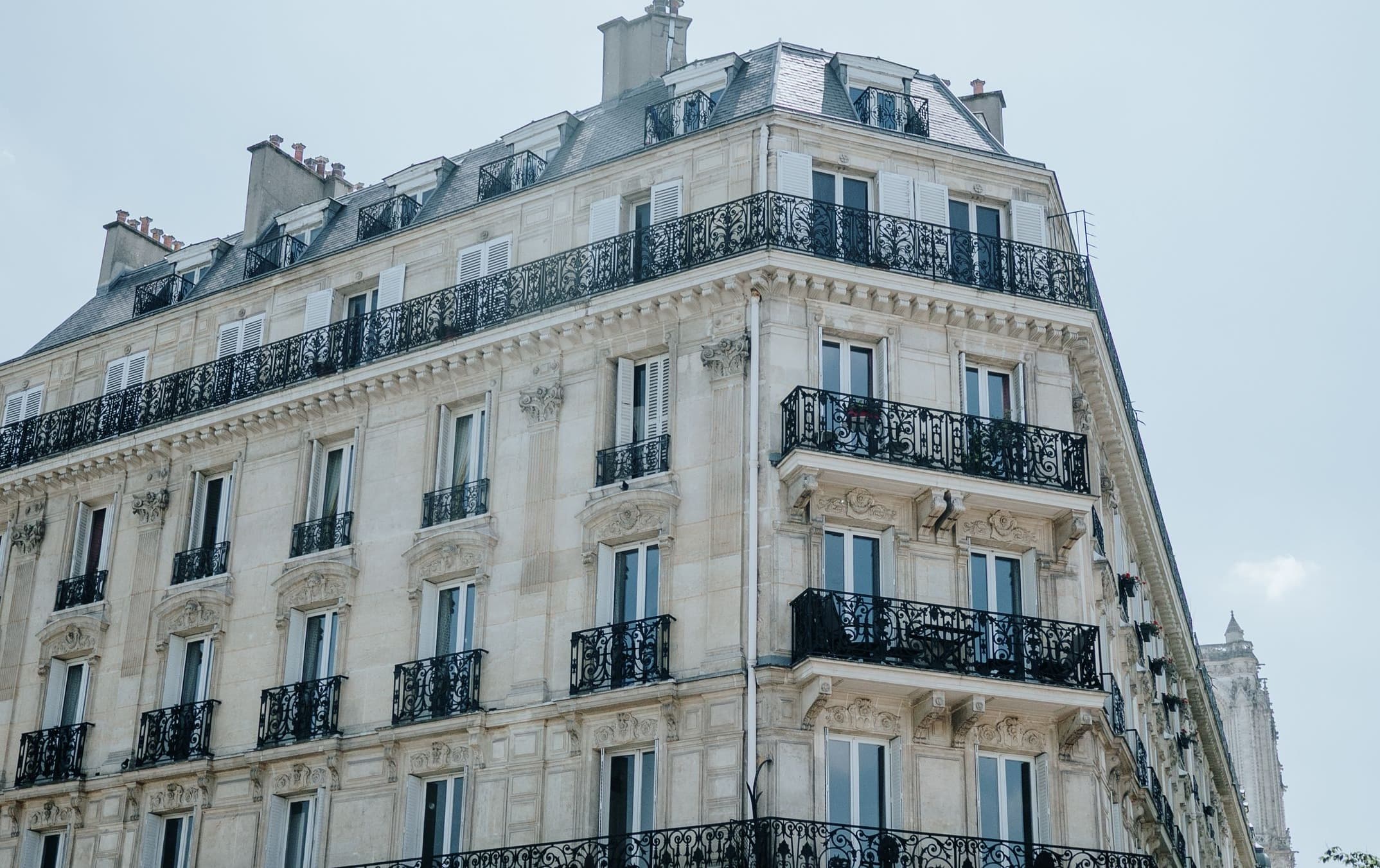 Façade d'un immeuble haussmannien à Paris, balcons en fer forgé et toit mansardé