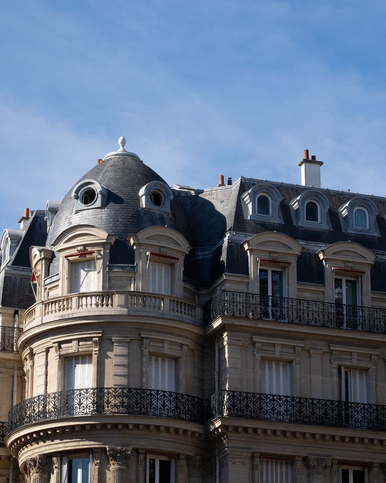 Immeuble haussmannien d'angle à Paris, façade en pierre de taille et toit en ardoise